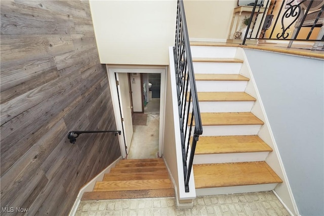 stairway featuring wood walls