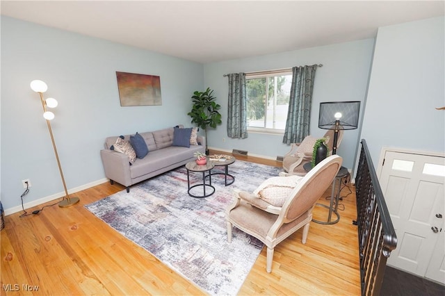 living area featuring visible vents, baseboards, and wood finished floors