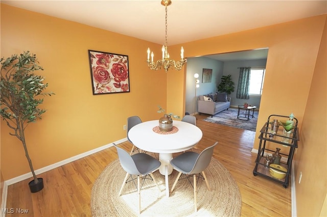 dining space featuring an inviting chandelier, baseboards, and light wood-style floors