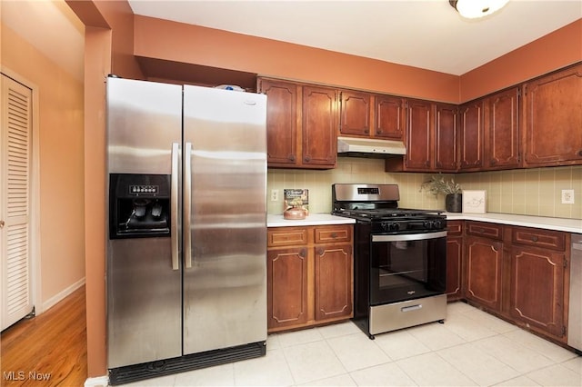 kitchen with stainless steel appliances, decorative backsplash, light countertops, and under cabinet range hood