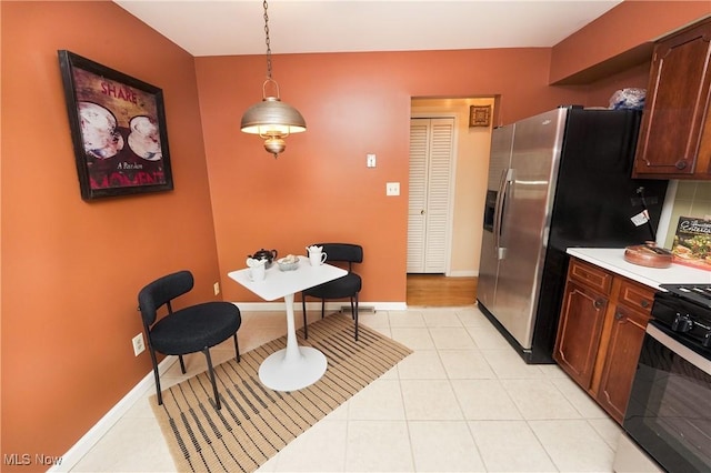 kitchen with light tile patterned floors, light countertops, baseboards, and gas range