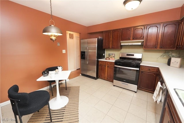 kitchen with decorative backsplash, appliances with stainless steel finishes, light countertops, under cabinet range hood, and pendant lighting