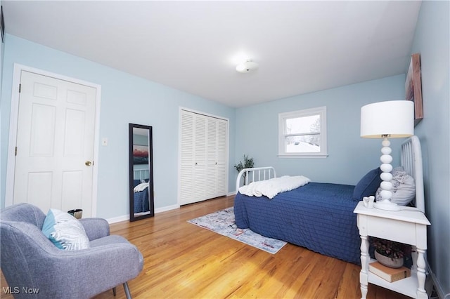 bedroom featuring light wood-type flooring, baseboards, and a closet