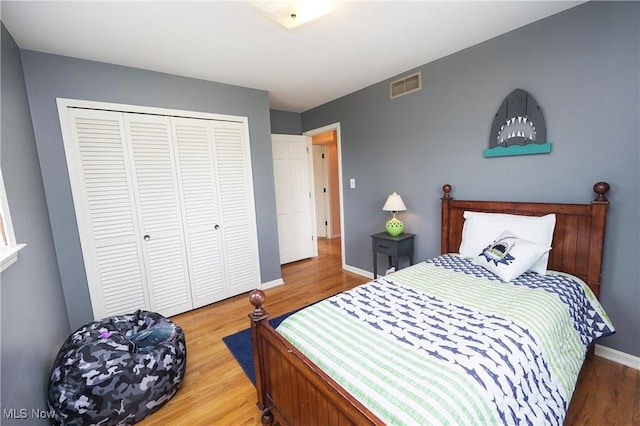 bedroom featuring a closet, wood finished floors, visible vents, and baseboards