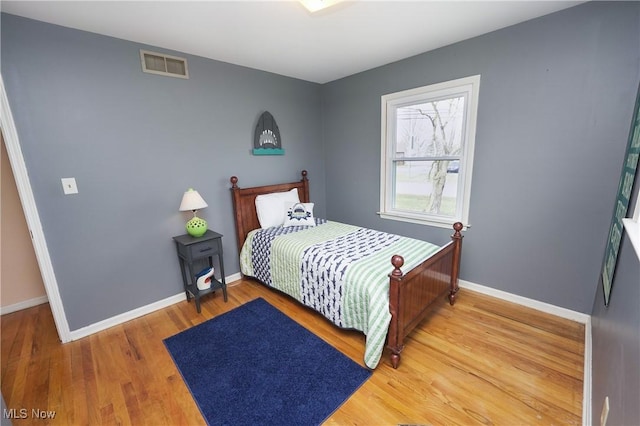 bedroom featuring light wood finished floors, baseboards, and visible vents