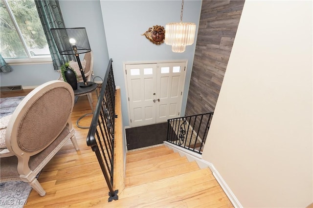 foyer with stairs, baseboards, wood finished floors, and an inviting chandelier