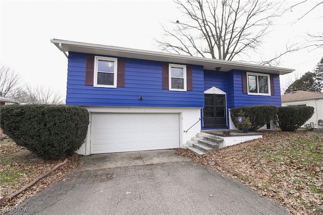 raised ranch featuring an attached garage and driveway