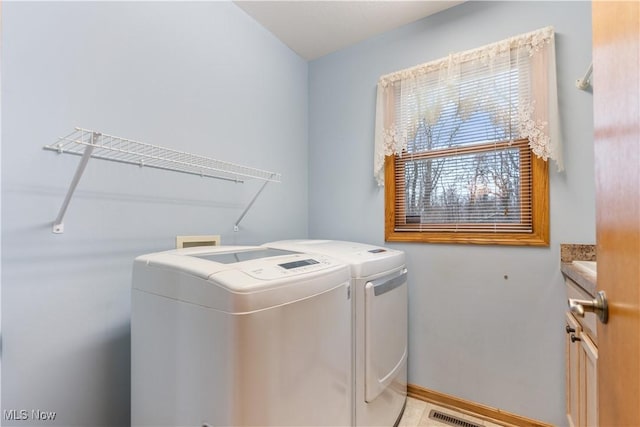 washroom with baseboards, visible vents, cabinet space, and washer and dryer