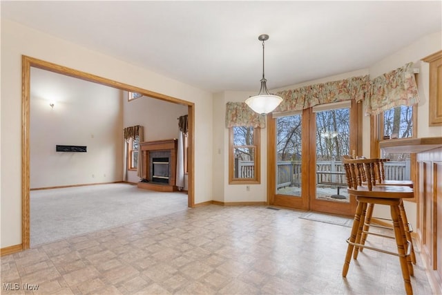 unfurnished dining area featuring light floors, a fireplace, and baseboards