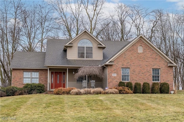 view of front of house featuring a porch, a front yard, brick siding, and a shingled roof