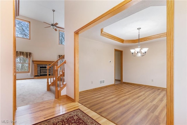 interior space with baseboards, visible vents, a raised ceiling, wood finished floors, and stairs