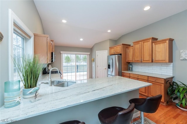 kitchen featuring lofted ceiling, a breakfast bar area, stainless steel appliances, a peninsula, and a sink