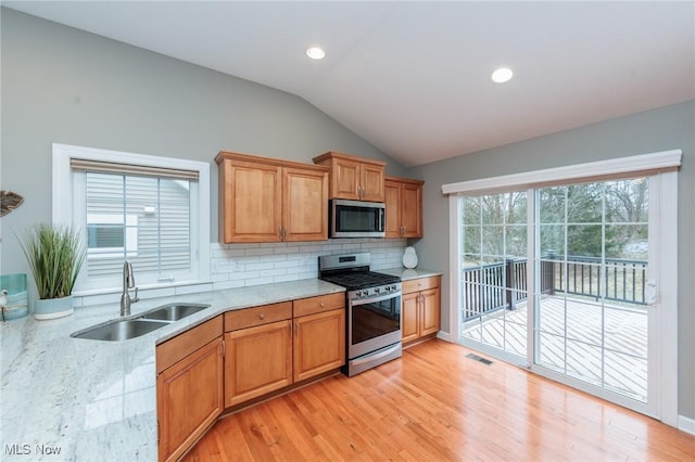 kitchen featuring tasteful backsplash, lofted ceiling, visible vents, appliances with stainless steel finishes, and a sink