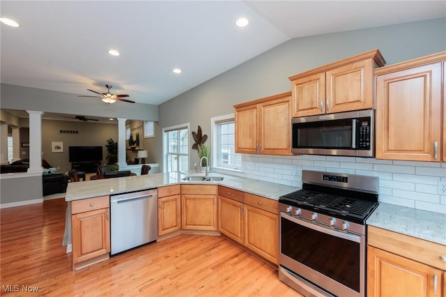 kitchen with stainless steel appliances, a peninsula, a sink, a ceiling fan, and decorative columns