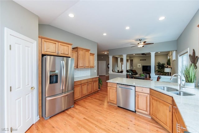 kitchen with light wood finished floors, a ceiling fan, appliances with stainless steel finishes, ornate columns, and a sink