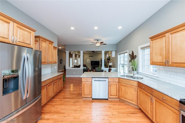 kitchen with decorative columns, stainless steel appliances, open floor plan, a sink, and ceiling fan