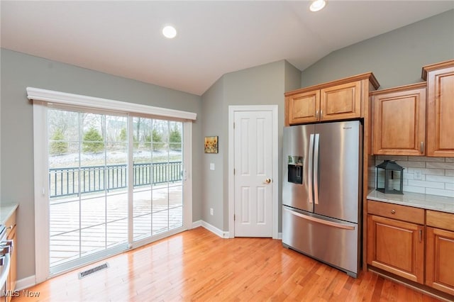 kitchen with visible vents, decorative backsplash, vaulted ceiling, light countertops, and stainless steel refrigerator with ice dispenser