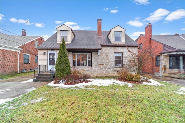 view of front of property with stone siding, a front lawn, and a chimney