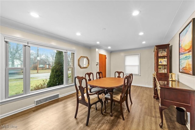 dining room featuring a healthy amount of sunlight, baseboards, visible vents, and wood finished floors