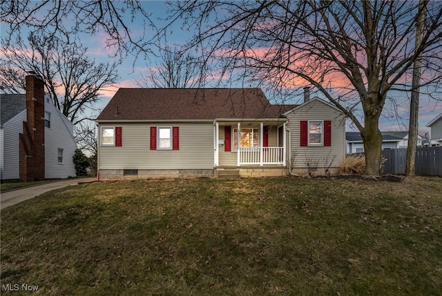 view of front of home with roof with shingles, fence, a porch, and a yard