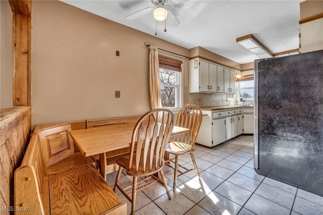 kitchen with light tile patterned floors, tasteful backsplash, freestanding refrigerator, and a healthy amount of sunlight