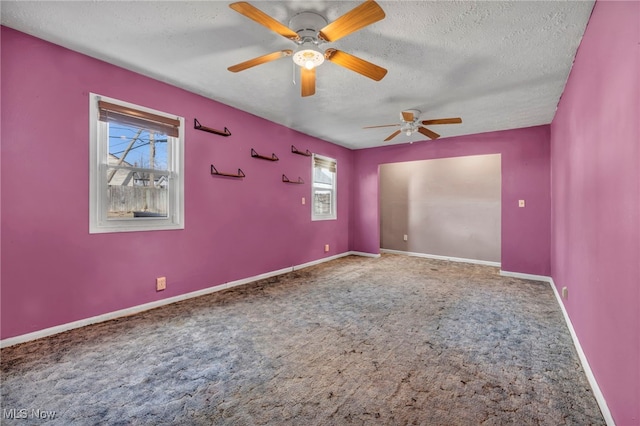 carpeted empty room featuring ceiling fan, a textured ceiling, and baseboards