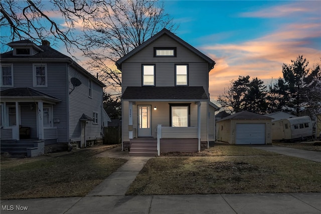 traditional-style home featuring driveway, a garage, an outbuilding, a porch, and a front yard