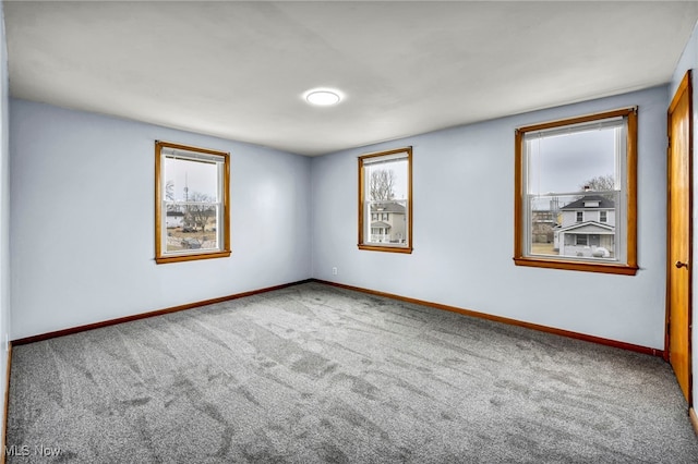 carpeted empty room featuring a wealth of natural light and baseboards