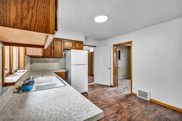 kitchen with a sink, visible vents, light countertops, freestanding refrigerator, and dark wood finished floors