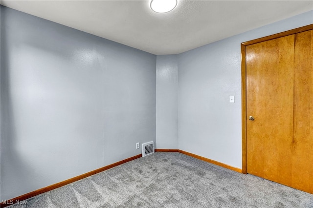 unfurnished room featuring carpet floors, visible vents, and baseboards