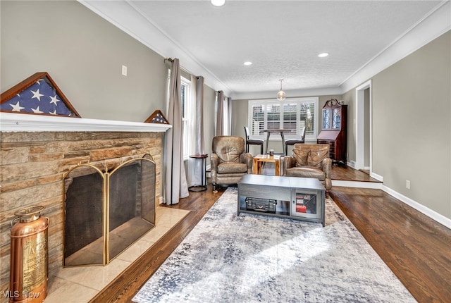 sitting room featuring a fireplace with flush hearth, crown molding, baseboards, and wood finished floors