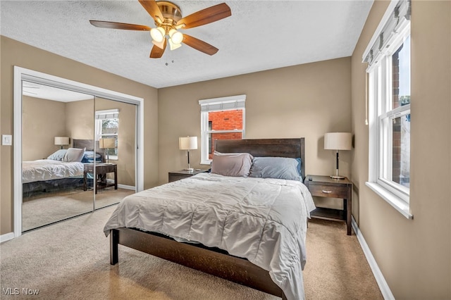 carpeted bedroom featuring a closet, multiple windows, a textured ceiling, and baseboards