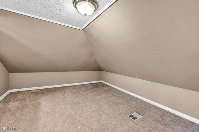 bonus room with baseboards, visible vents, vaulted ceiling, and carpet flooring