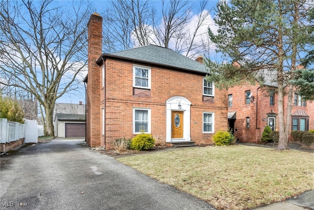 view of front of property with a chimney, an outbuilding, fence, a front lawn, and brick siding