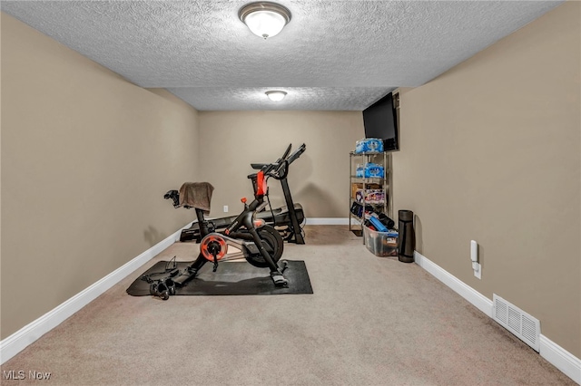 exercise area featuring a textured ceiling, carpet, visible vents, and baseboards