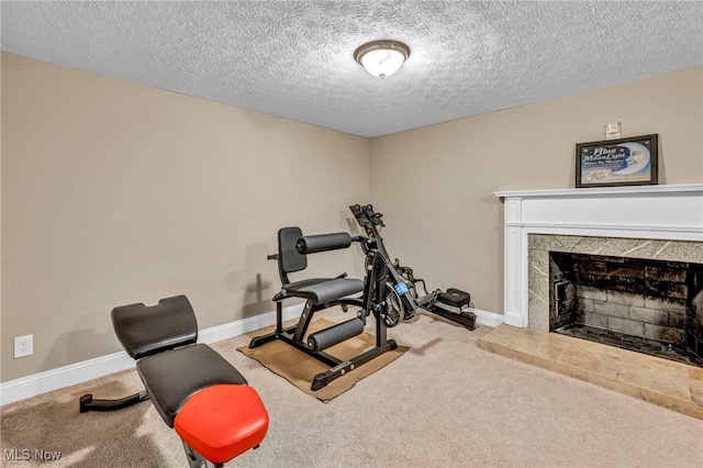 exercise area with a textured ceiling, carpet, a fireplace, and baseboards