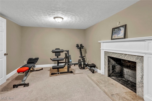 exercise room with carpet flooring, a textured ceiling, baseboards, and a premium fireplace