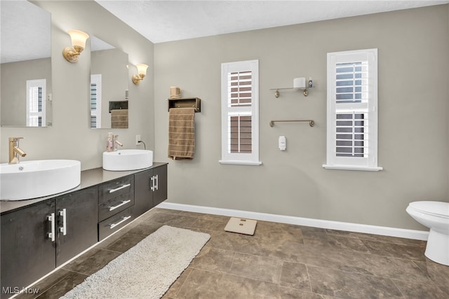 full bathroom with double vanity, baseboards, and a sink