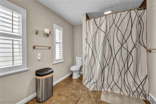 bathroom featuring visible vents, baseboards, a shower with shower curtain, toilet, and a textured ceiling