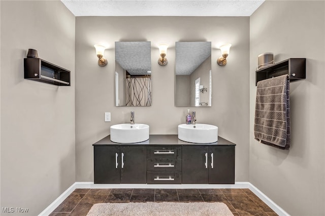 bathroom featuring a textured ceiling, baseboards, and a sink