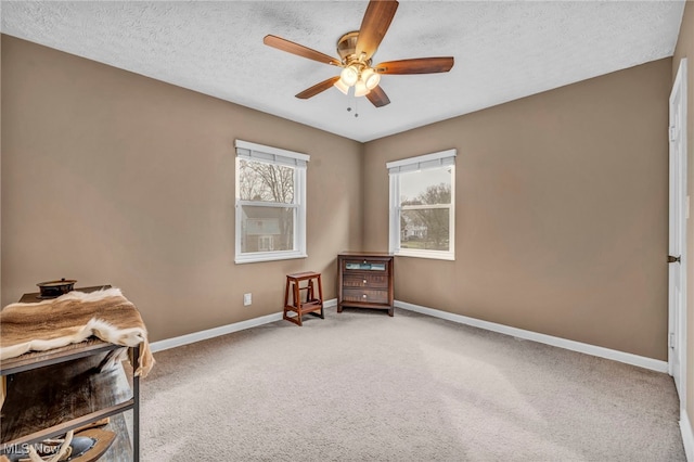 sitting room with a ceiling fan, carpet, baseboards, and a textured ceiling