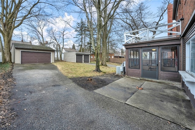 view of yard with an outdoor structure, a detached garage, and central AC unit