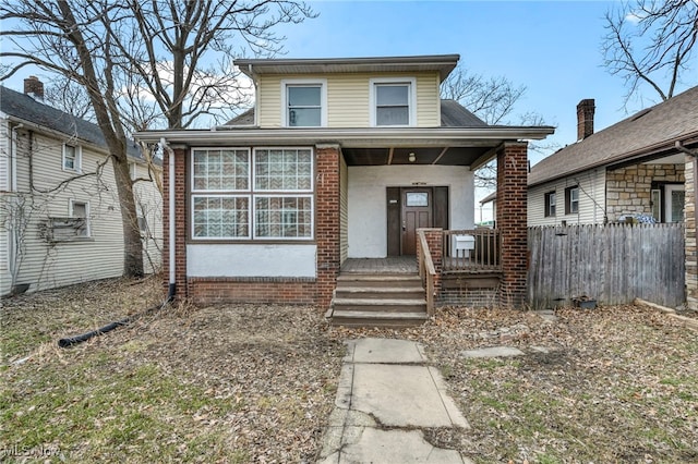 bungalow featuring covered porch, fence, and stucco siding