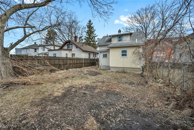 back of house with a chimney and fence