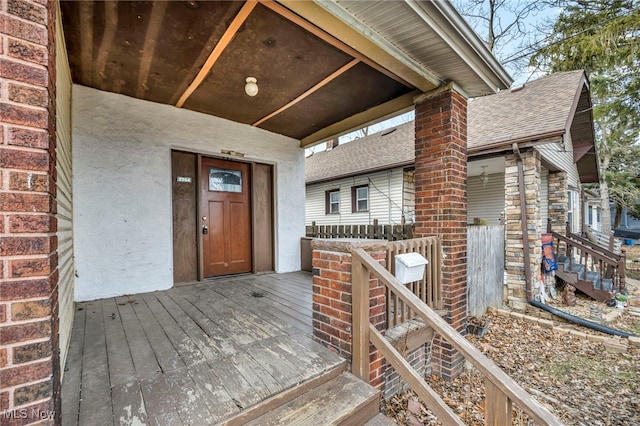 view of exterior entry featuring a deck and roof with shingles