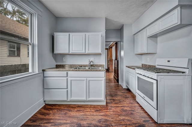 kitchen with white gas range, white cabinetry, dark wood finished floors, and a sink