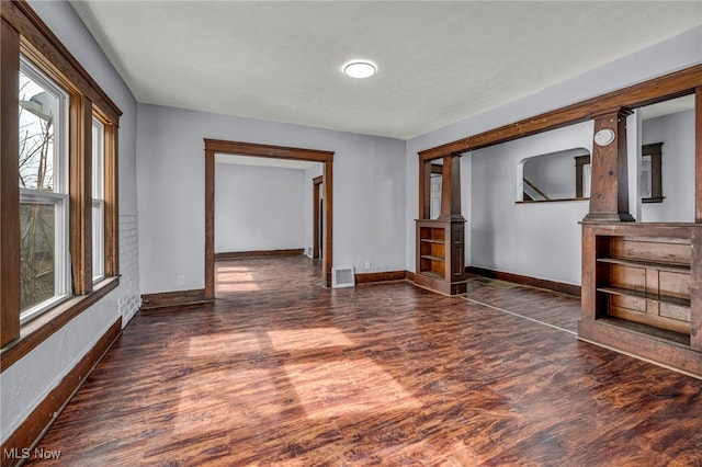 unfurnished room featuring baseboards, visible vents, and wood finished floors