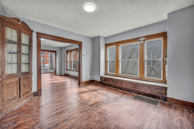 spare room featuring baseboards, a textured ceiling, visible vents, and wood finished floors