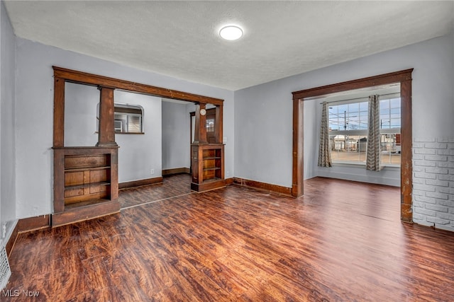 empty room featuring a textured ceiling, baseboards, and wood finished floors