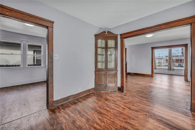 spare room featuring baseboards and wood finished floors